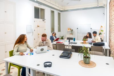 Espace de coworking lumineux avec bureaux partagés, ordinateurs et plantes d'intérieur