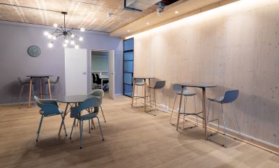 Espace de coworking avec design industriel, tables hautes et basses, chaises ergonomiques et éclairage soigné.