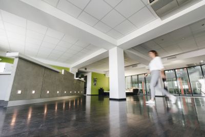 Lobby lumineux avec design contemporain, plafond blanc, sol en bois et touches de vert