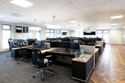 Espace de travail collaboratif avec bureaux en îlots, moniteurs et chaises ergonomiques